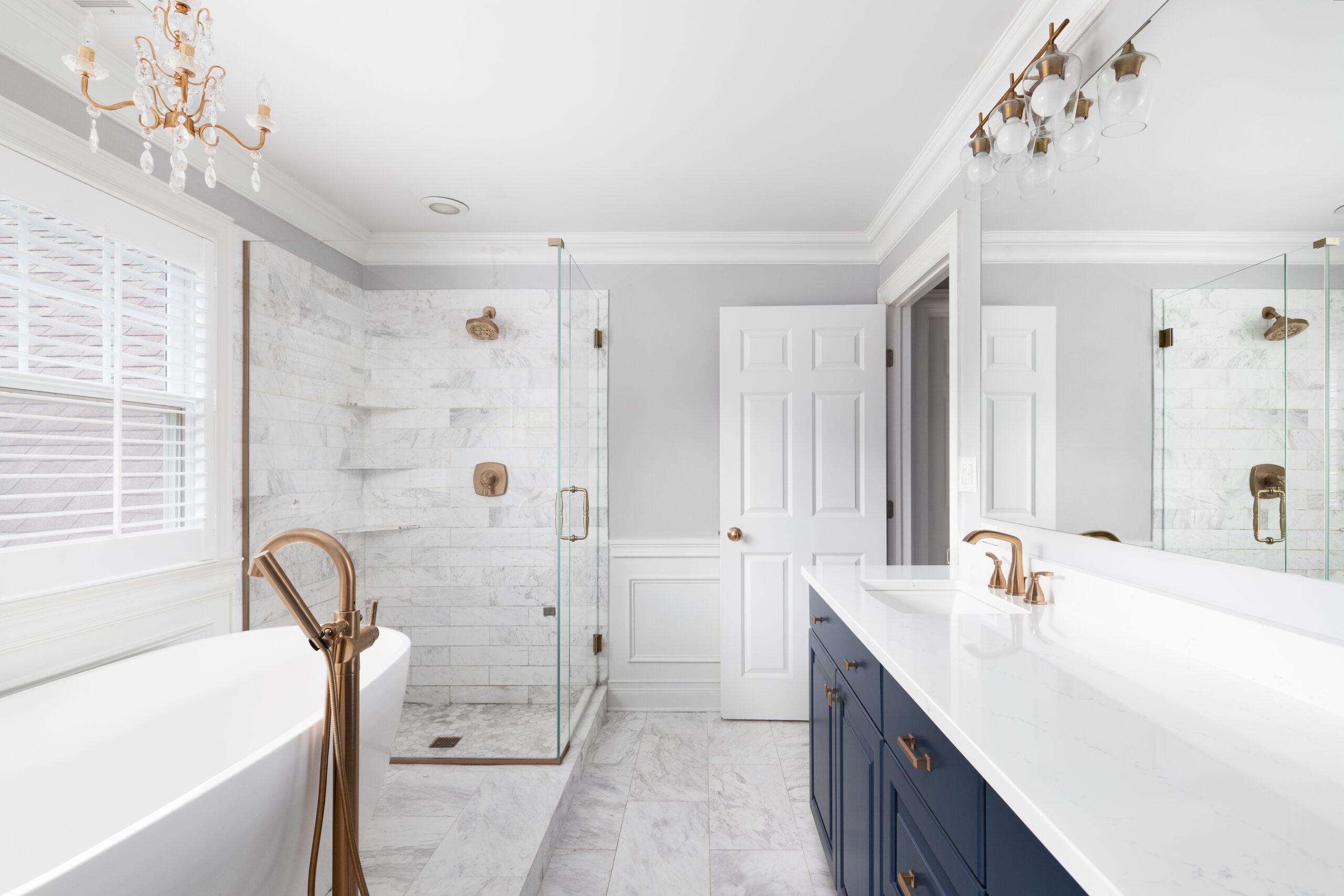 A beautiful bathroom with a blue vanity cabinet, standalone bath